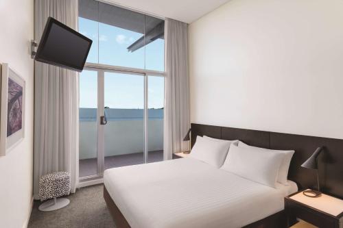 a bedroom with a bed and a large window at Adina Apartment Hotel Perth in Perth