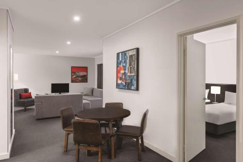 a living room with a table and a bedroom at Adina Apartment Hotel Perth Barrack Plaza in Perth