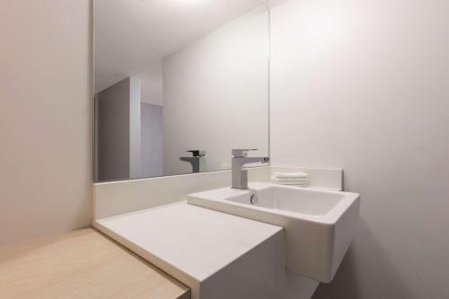 ein weißes Badezimmer mit einem Waschbecken und einem Spiegel in der Unterkunft Rendezvous Hotel Perth Central in Perth