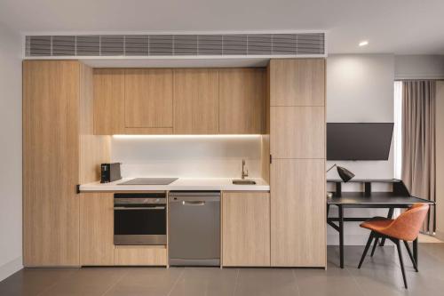 a kitchen with wooden cabinets and a sink and a stove at Vibe Hotel Canberra in Canberra