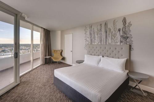 Cette chambre comprend un lit et une grande fenêtre. dans l'établissement Rendezvous Hotel Perth Scarborough, à Perth