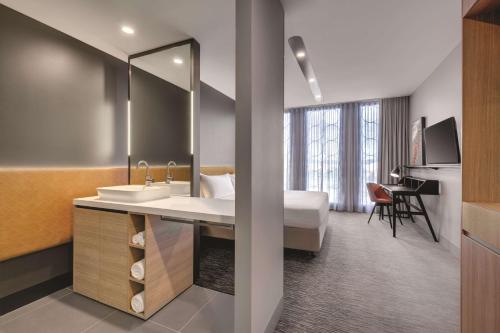 Habitación de hotel con baño con lavabo y cama en Vibe Hotel Canberra en Canberra
