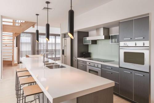 a kitchen with a white counter top and a kitchen island at Adina Apartment Hotel Auckland Britomart in Auckland