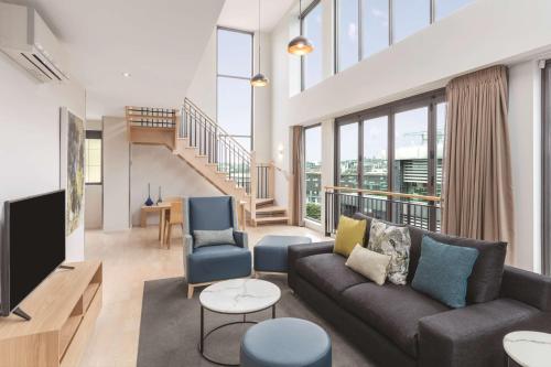 a living room with a couch and a tv at Adina Apartment Hotel Auckland Britomart in Auckland