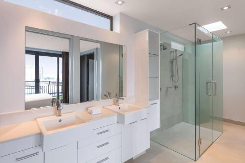 a bathroom with two sinks and a glass shower at Adina Apartment Hotel Auckland Britomart in Auckland