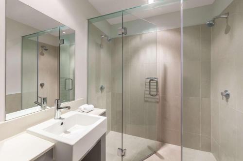 a bathroom with a sink and a glass shower at Adina Apartment Hotel Auckland Britomart in Auckland