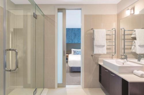 a bathroom with a glass shower and a sink at Adina Apartment Hotel Auckland Britomart in Auckland