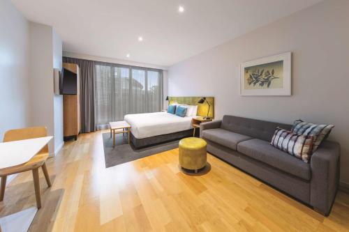 a living room with a couch and a bed at Adina Apartment Hotel Auckland Britomart in Auckland