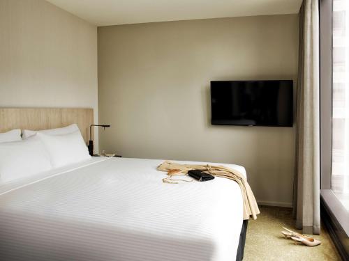 a bedroom with a large white bed and a flat screen tv at A by Adina Sydney in Sydney