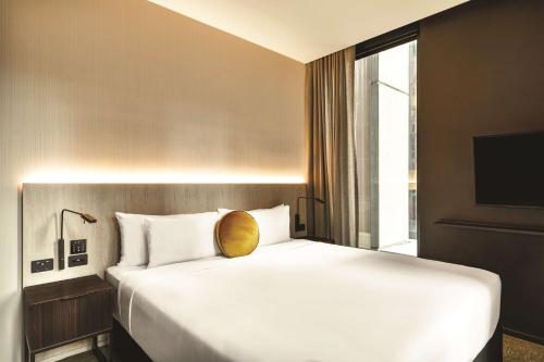 a bedroom with a large white bed with a large window at A by Adina Sydney in Sydney