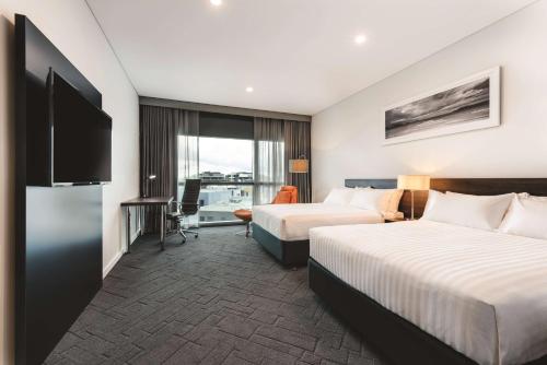 a hotel room with two beds and a television at Vibe Hotel Subiaco Perth in Perth