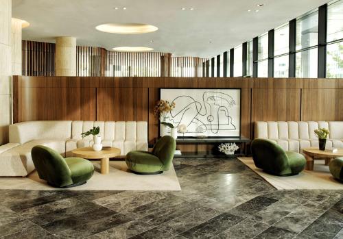 a lobby with green chairs and a drawing on the wall at A by Adina Canberra in Canberra