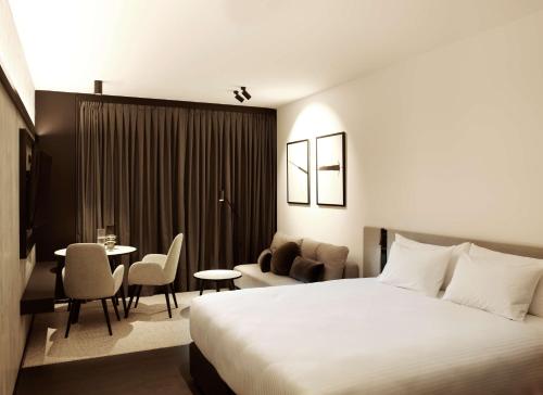a hotel room with a bed and a table and chairs at A by Adina Canberra in Canberra