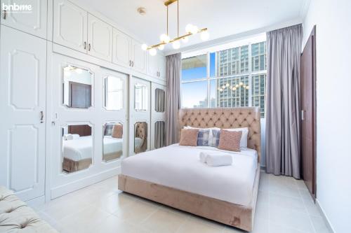 a white bedroom with a bed and a large window at bnbmehomes - 2BR Apt with Burj Khalifa View -1406 in Dubai