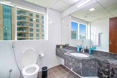 a bathroom with a toilet and a sink and a window at bnbmehomes - 2BR Apt with Burj Khalifa View -1406 in Dubai
