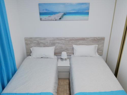 two beds in a room with a painting on the wall at THREE BEDROOM APARTAMENT II NEAR SANTA CRUZ in Santa Cruz de Tenerife