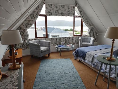 1 dormitorio con 1 cama, sillas y ventanas en Yellowwood Lodge, en Knysna
