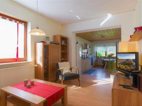 ein Wohnzimmer mit einem Tisch und einem TV sowie eine Küche in der Unterkunft Ferienwohnung Leipold Andreas in Merzig