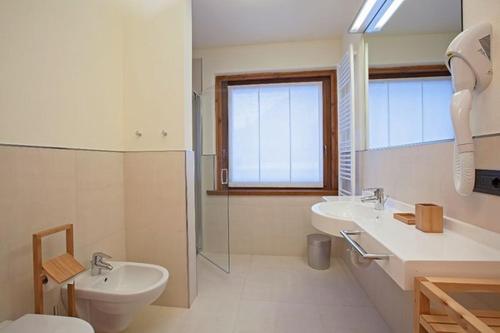 a bathroom with two sinks and a toilet and a window at Appartamenti Mottini Plaza in Livigno