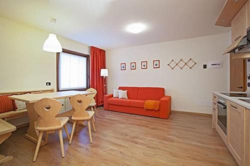 a living room with a red couch and a table and chairs at Appartamenti Mottini Plaza in Livigno
