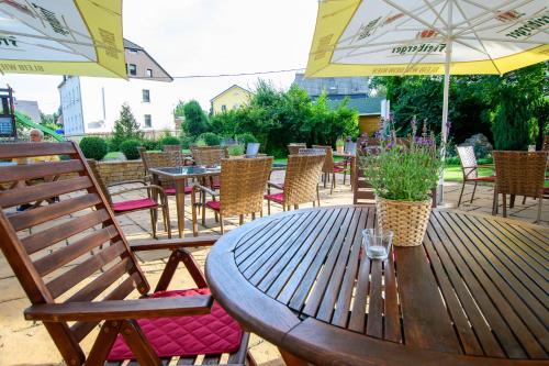 a wooden table with chairs and tables and umbrellas at Erzgebirgshotel Freiberger Höhe in Eppendorf