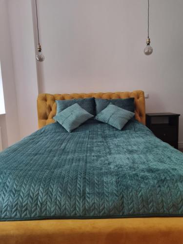 a bed with a green comforter and blue pillows at Apartament w kamienicy in Poznań