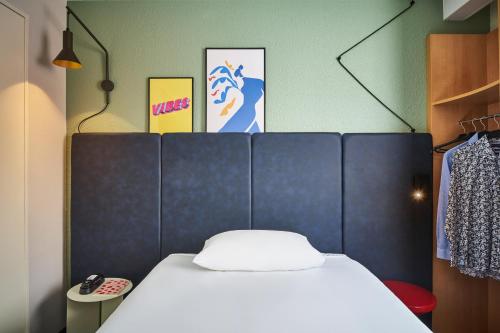 a bed with a blue headboard in a room at ibis Paris Avenue d'Italie 13ème in Paris