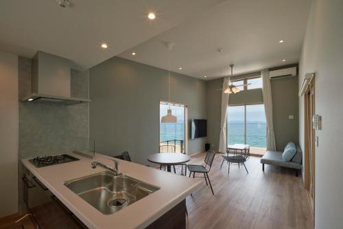 a kitchen and living room with a sink and a table at ALFACIO RESORT STAY ITOSHIMA in Itoshima