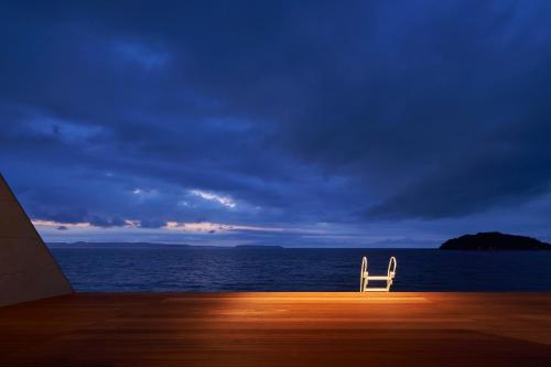 a white chair sitting on a deck looking out at the ocean at ALFACIO RESORT STAY ITOSHIMA in Itoshima