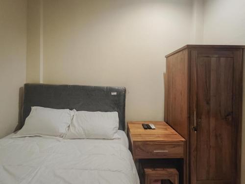 ein Schlafzimmer mit einem Bett mit einem hölzernen Nachttisch und einem Bett mit einem sidx sidx sidx in der Unterkunft KoolKost @ Gatot Subroto Timur Denpasar in Denpasar