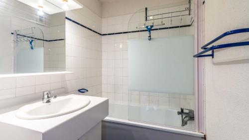 uma casa de banho branca com um lavatório e um chuveiro em Les Sitelles - 11 - Piscine Appart 6 pers em Morillon
