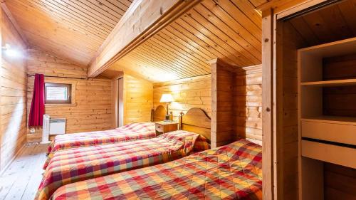 um quarto com 2 camas num chalé de madeira em Bois de Champelle- 94 Magnifique Chalet-10 pers em Morillon