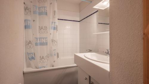 a bathroom with a sink and a shower curtain at Les Eterlous - 39- Appart pied des pistes 6 pers in Morillon