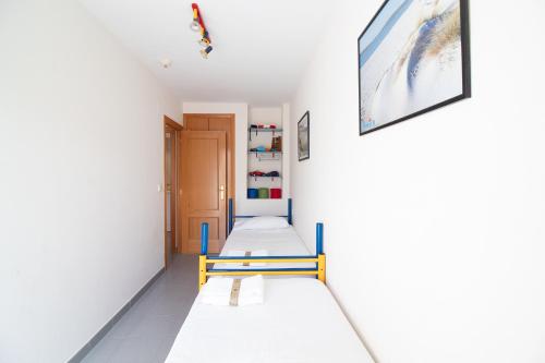 una fila di letti in una stanza con pareti bianche di Global Properties, Atico con gran terraza y barbacoa a Canet de Berenguer