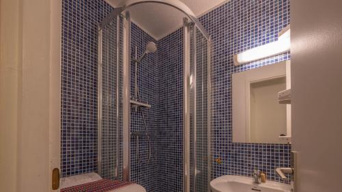 y baño de azulejos azules con ducha y lavamanos. en Le Grand Neige - 36 - Appart Montagne 6 pers en Morillon