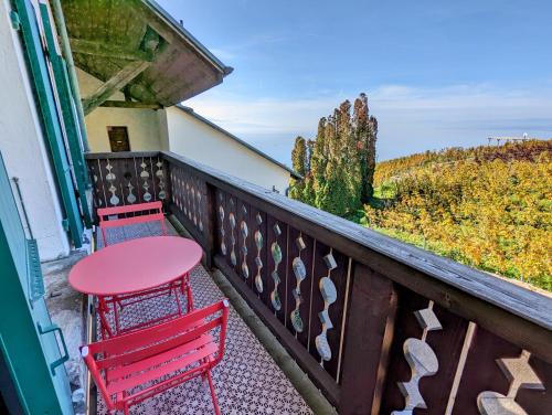 a balcony with two red chairs and a table at Domaine de la Crausaz in Grandvaux