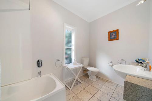a bathroom with a tub and a sink and a toilet at Te Kawa Cottage - Martinborough Holiday Home in Martinborough