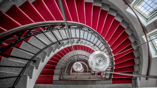 a red spiral staircase in a building with a window at Clarion Collection Hotel Post in Oskarshamn