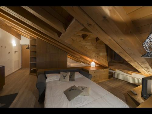 a large bed in a room with wooden ceilings at Appartamento Jardin des Alpes. in La Thuile