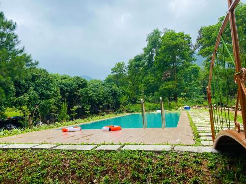 uma piscina com objectos laranja num deque de madeira em Moon Villa Soc Son - Venuestay em Hanói