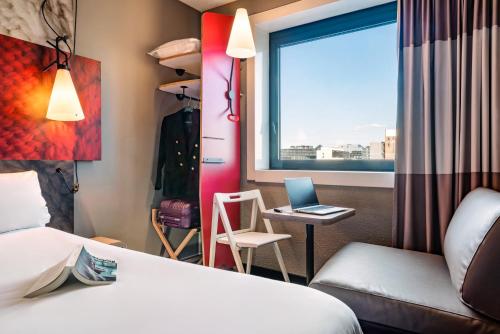 a hotel room with a bed and a desk with a laptop at Ibis Marne la Vallée Noisy in Noisy-le-Grand