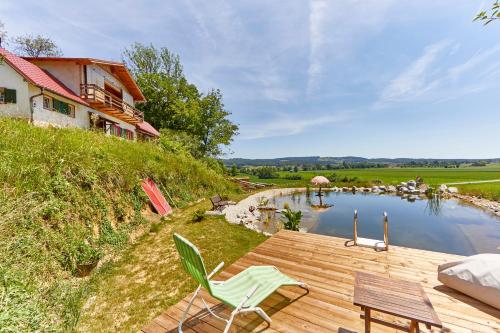 a wooden deck with chairs next to a lake at Exklusives Zimmer im Kräuterstöckl mit Frühstück gegen Aufpreis in Muggendorf