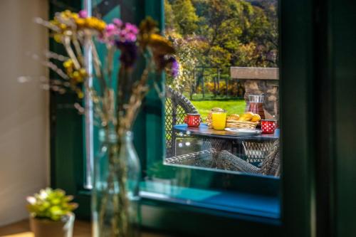 a table with a plate of food and flowers in a window at Ferrata Vár Vendégház in Csesznek