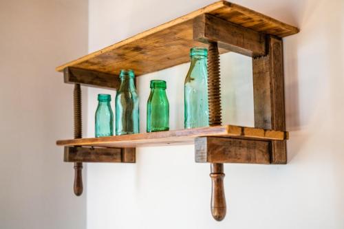 a wooden shelf with green glass bottles on a wall at Ferrata Vár Vendégház in Csesznek