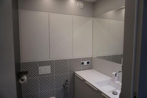 Baño blanco con lavabo y espejo en Piękny apartament w zielonej dzielnicy Wrocławia, en Wroclaw