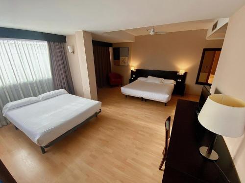 1 dormitorio con 2 camas y escritorio con lámpara en Spa Hotel Ciudad de Teruel, en Teruel