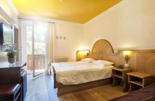 a bedroom with a bed and a large window at Grand Hotel Biancaneve in Folgaria