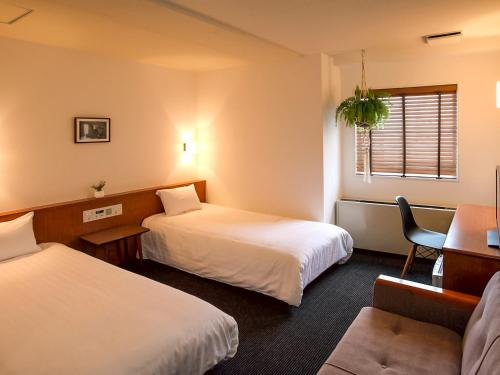 a hotel room with two beds and a chair at Hotel Pacific Kanazawa in Kanazawa