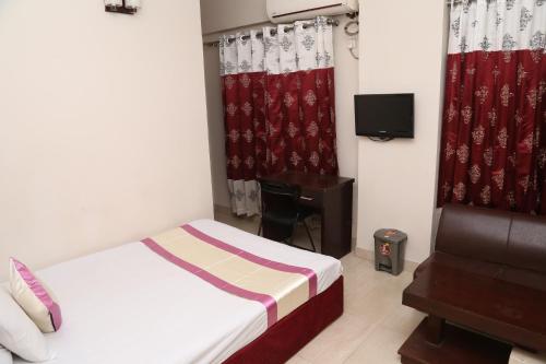 a bedroom with a bed and a desk and curtains at Platinum Hotel Ltd in Dhaka
