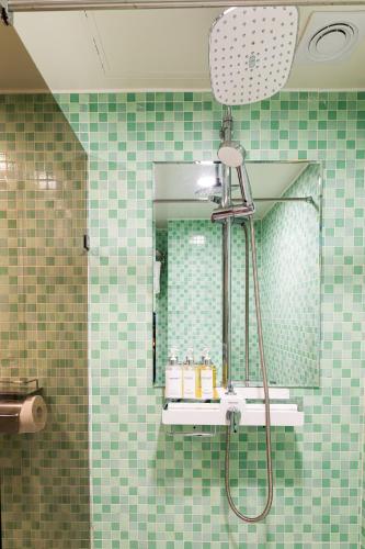 a green tiled bathroom with a shower and a mirror at HOTEL LENITH Seomyeon in Busan